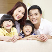 Portrait of smiling young Asian family with two grinning children.