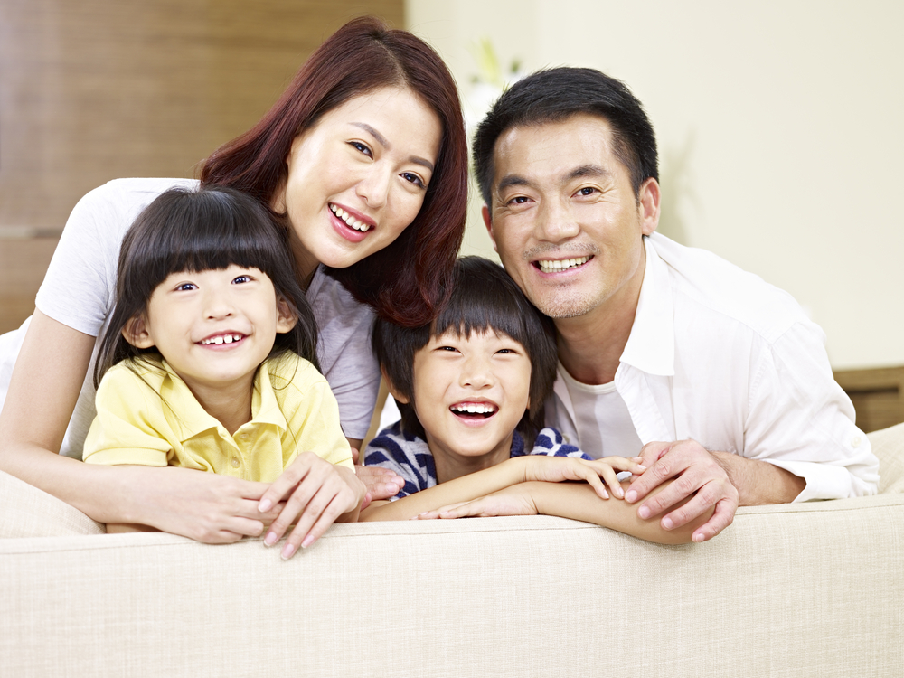 Portrait of smiling young Asian family with two grinning children.