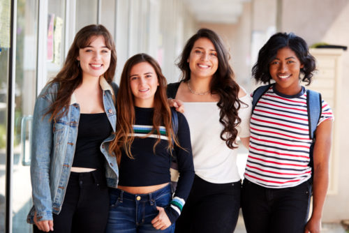 Smiling Female Students Friends In Corridor Of Building.