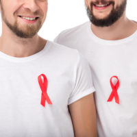Cropped shot of two smiling bearded men with aids ribbons