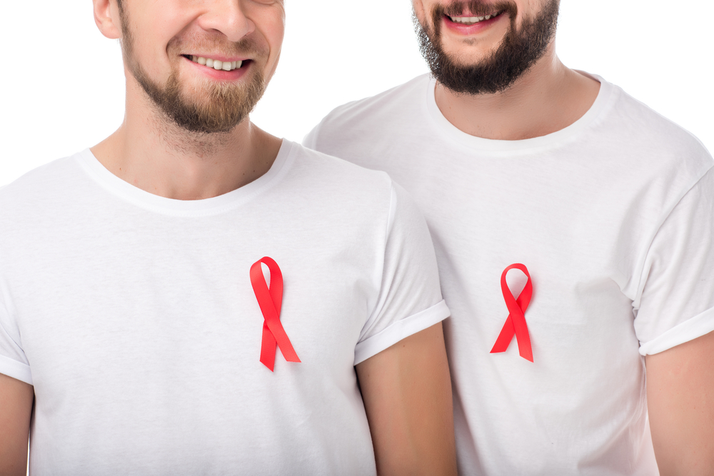 Cropped shot of two smiling bearded men with aids ribbons