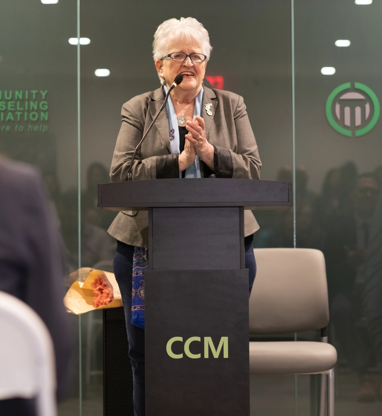 Commissioner Sullivan of OMH stands at podium and smiles while clasping her hands during her keynote speech.