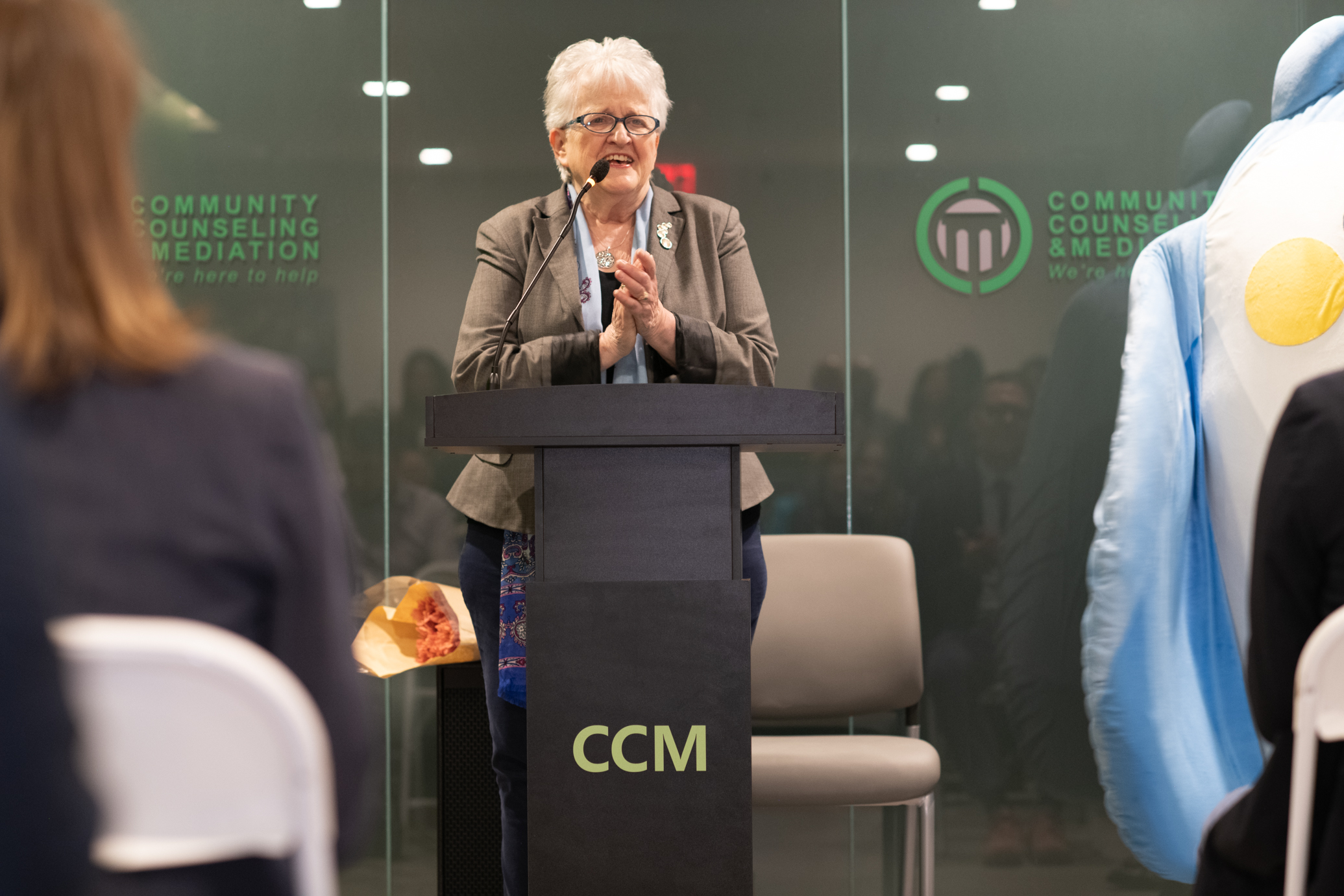 Commissioner Sullivan of OMH stands at podium and smiles while clasping her hands during her keynote speech.
